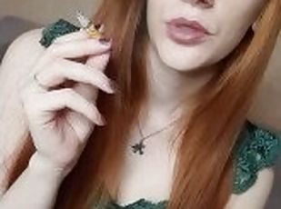 A red-haired girl with long hair smokes a cigarette with a brown