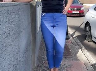 Girl peeing in jeans and walking on the public street